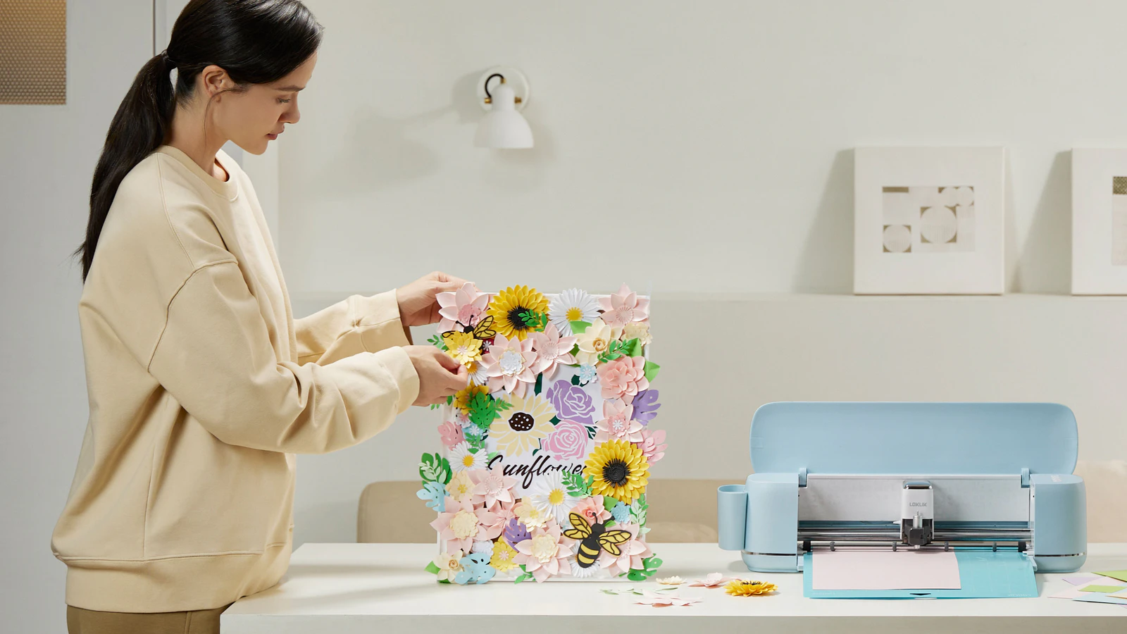 A maker arranging paper flowers beside a LOKLiK iCraft cutting machine