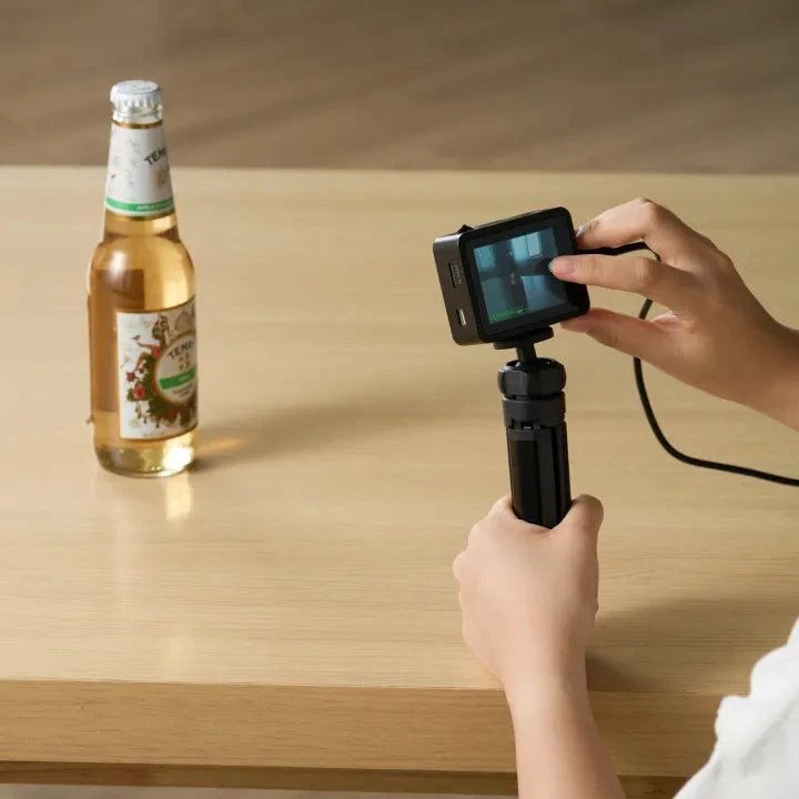 Person using the AI Camera on a small tripod to recognise a bottle on a table.