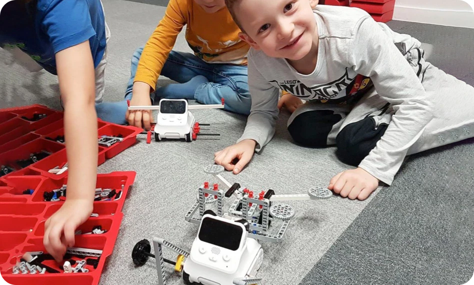 Children playing with Codey Rocky robots, construction bricks and a wheeled build.