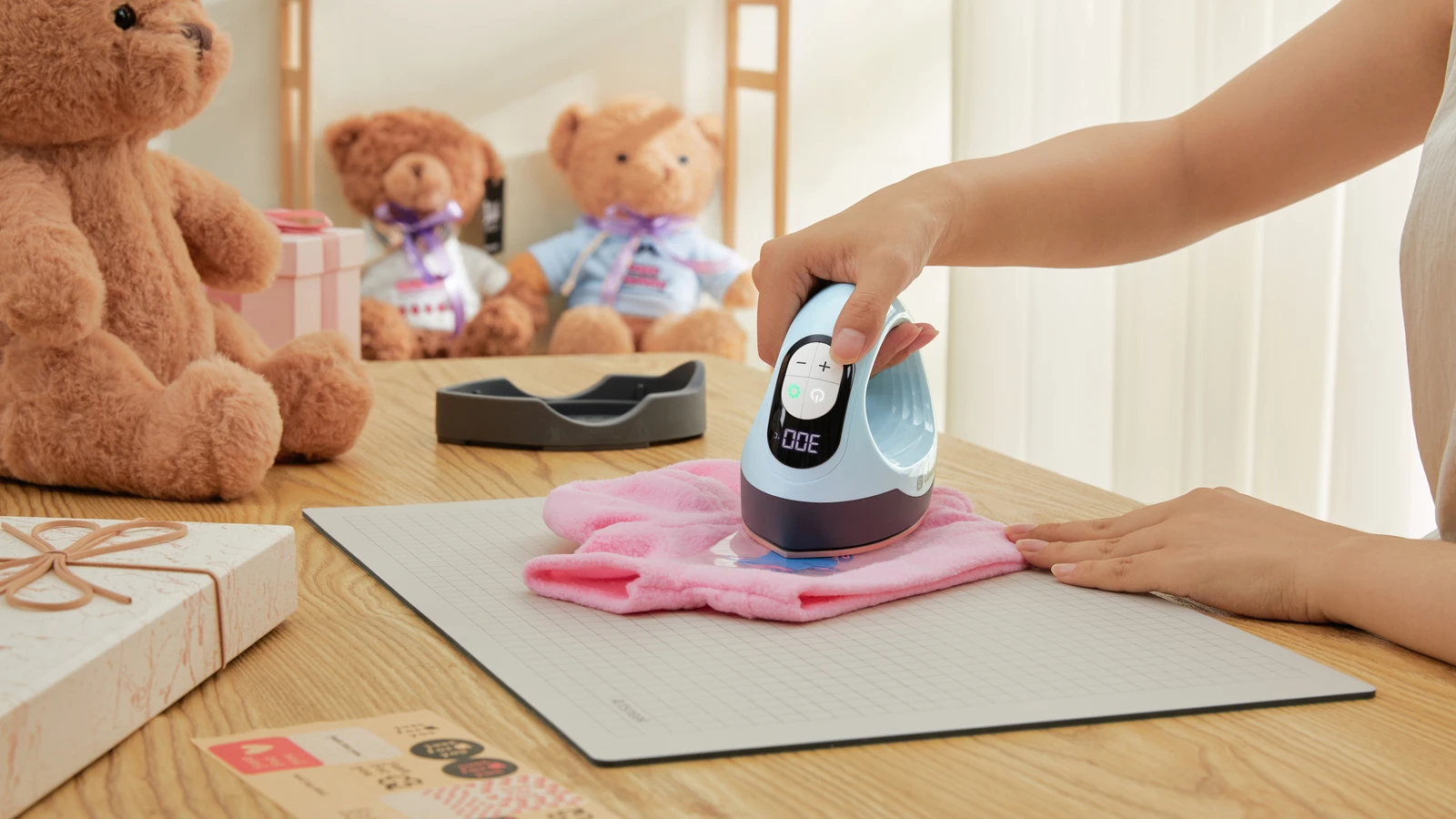 Blue LOKLiK ImPress Mini 3 applying a transfer to a pink fabric garment on a work surface.