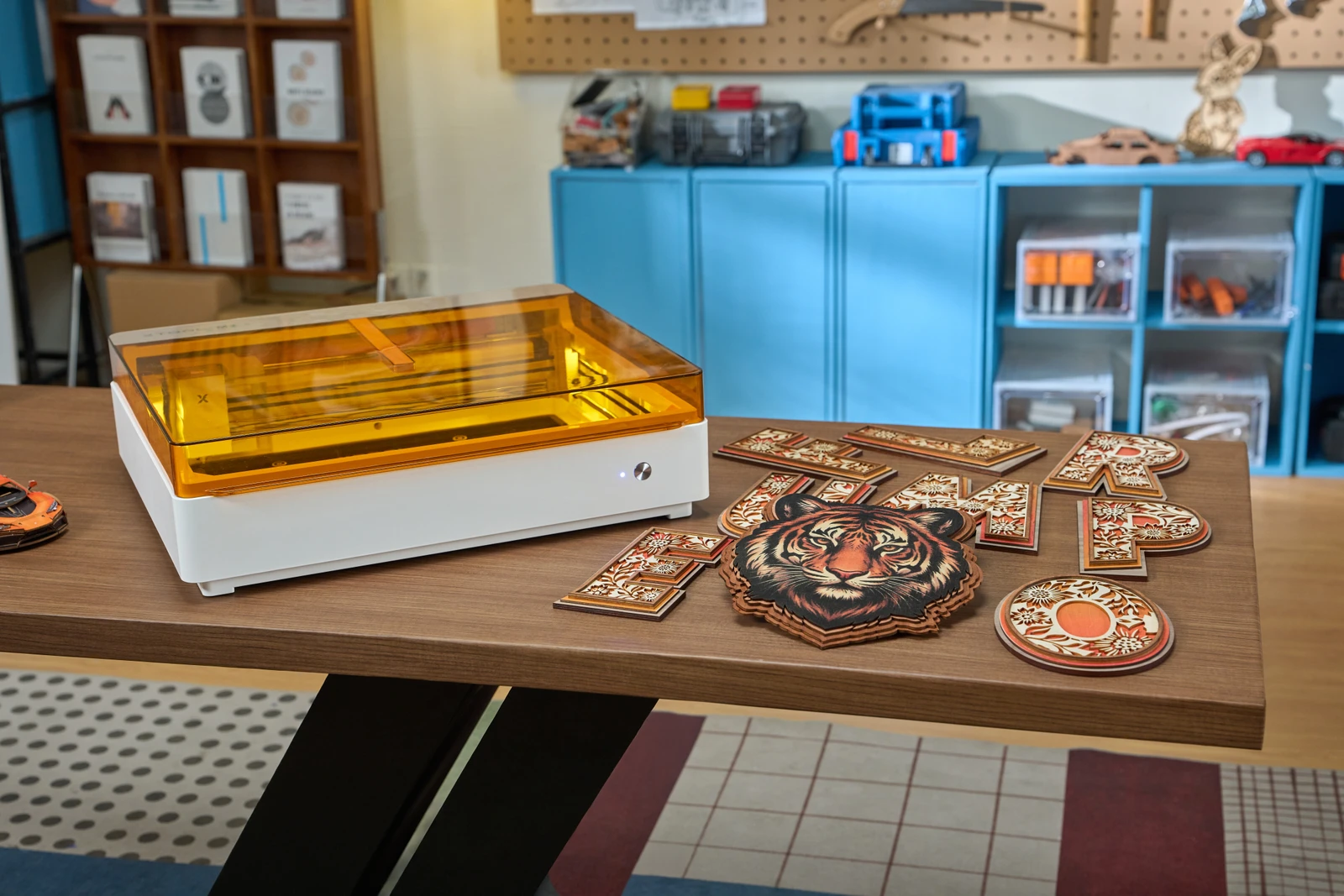 xTool M2 on a workshop table beside layered wooden signs and a tiger design.