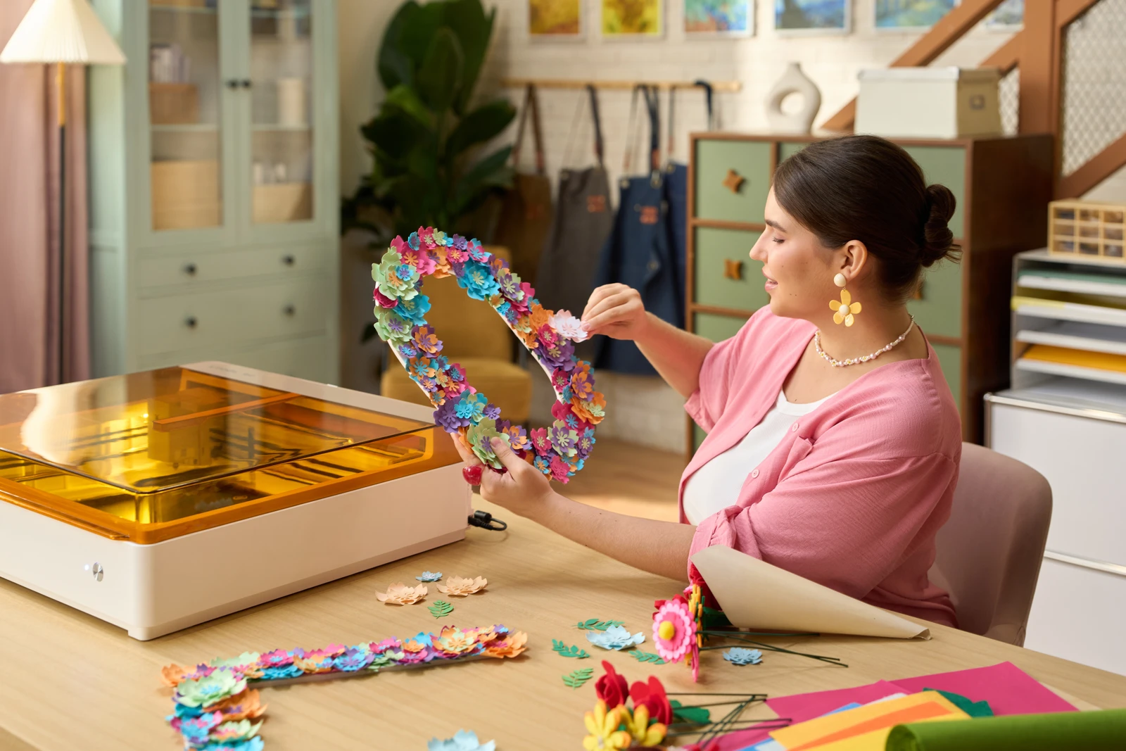 A maker assembling a colourful floral decoration beside an xTool M2.