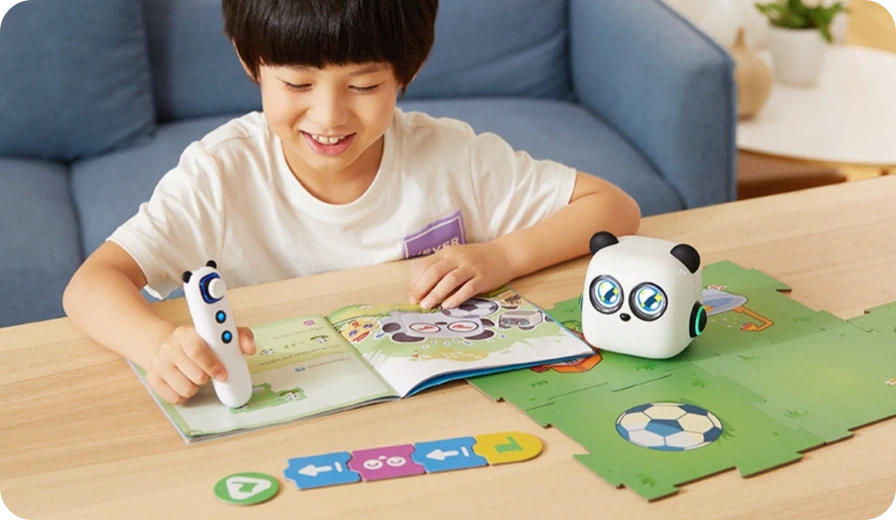 Child using an mTiny robot and tap pen at a table with a map and activity book.