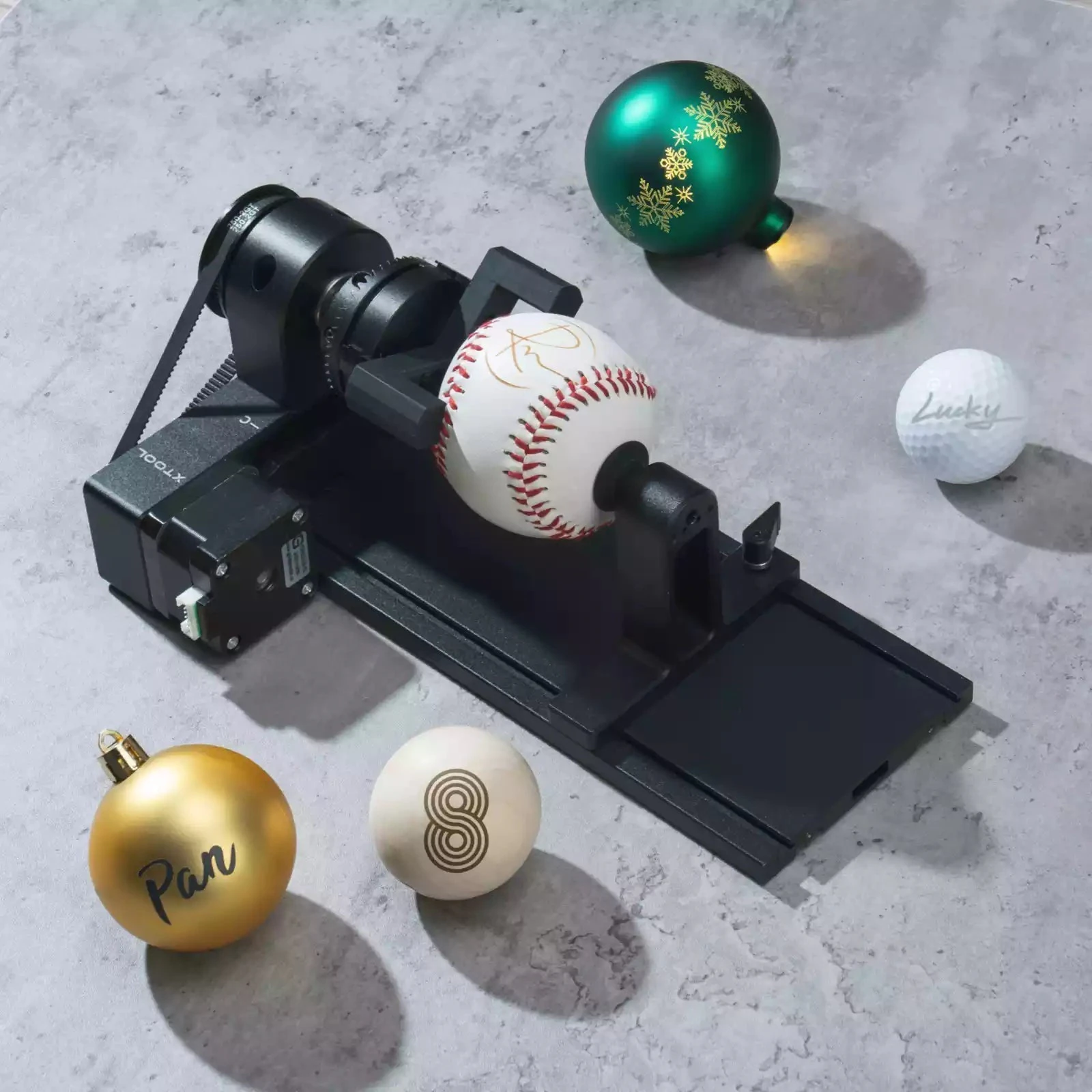 RA2 Pro holding a baseball, surrounded by engraved baubles, billiard ball and golf ball.